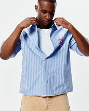 Mens Duncan Stripe Shirt, light blue with vertical white and dark blue stripes, featuring a large embroidered pink Psycho Bunny skull logo and script on the left chest, relaxed fit. (4)