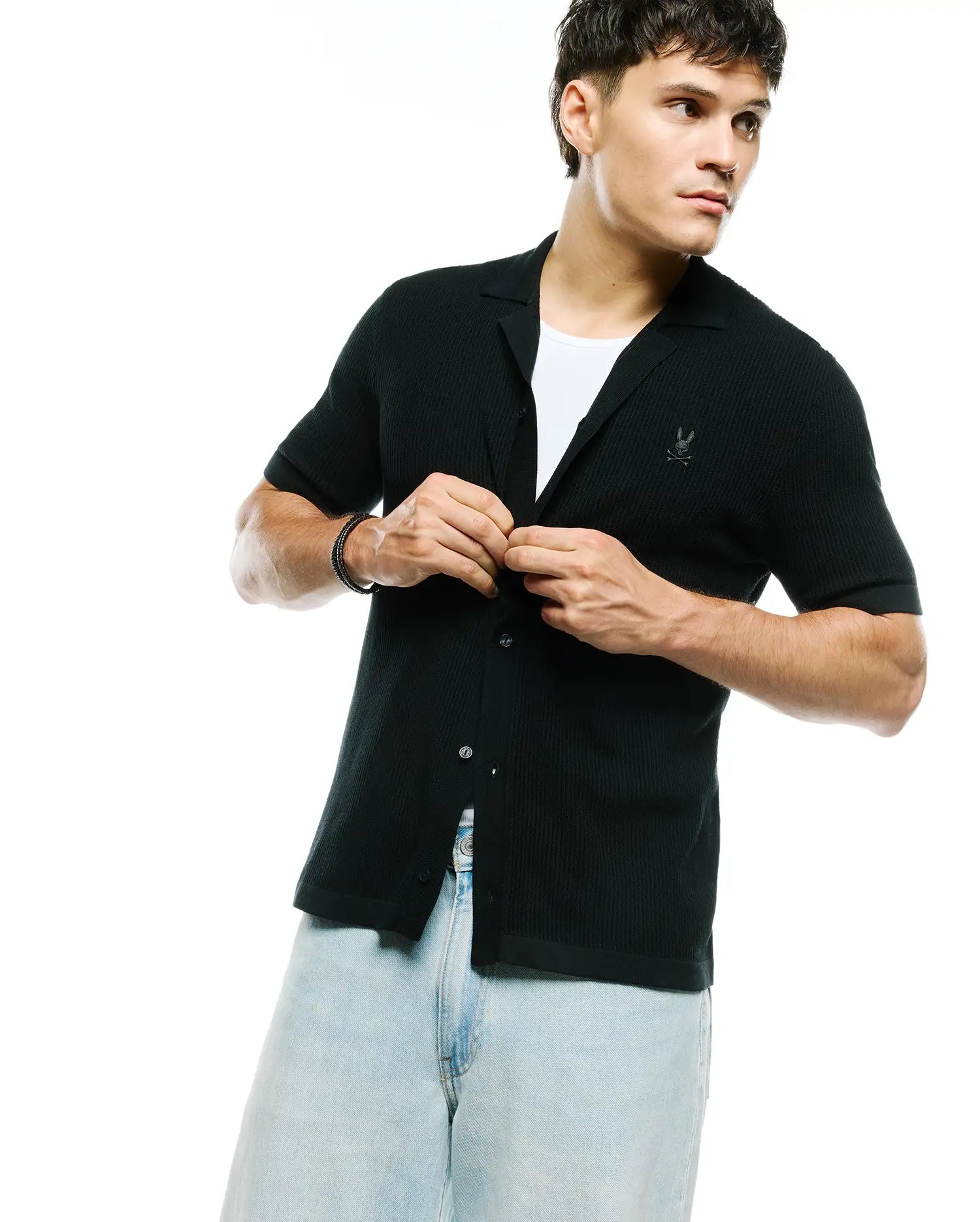Black Mens Yann Knit Shirt, a classic fit, short-sleeve, full button-front with a ribbed knit texture, spread collar, and a small embroidered Psycho Bunny skull logo on the left chest.