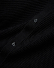 Mens Yann Knit Shirt, a sleek black premium ribbed knit garment, detailed with two dark buttons featuring the Psycho Bunny brand name embossed in a lighter tone.