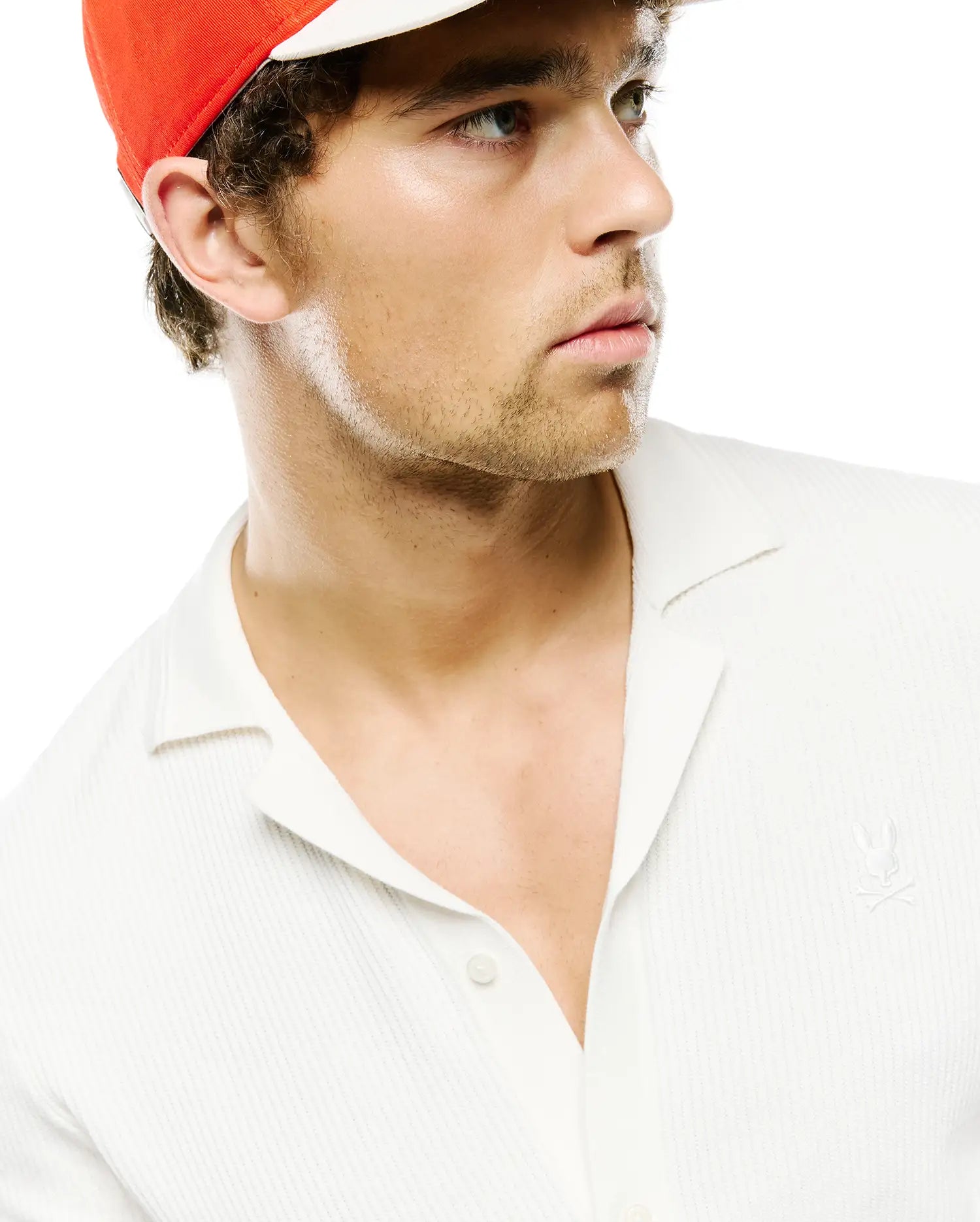 Mens Yann Knit Shirt, a classic fit white ribbed knit shirt featuring an open camp collar, two-button placket, and small embroidered Psycho Bunny skull logo on the left chest.