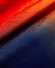 Mens Zander Jacquard Shirt fabric showcasing a vibrant red to deep navy gradient, subtly woven with an all-over Psycho Bunny skull logo jacquard pattern.