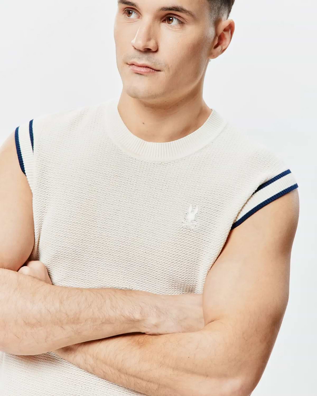 Peter Knit Vest, cream textured knit with navy double-striped ribbed armholes, classic fit, and a small embroidered Psycho Bunny skull logo on the left chest.