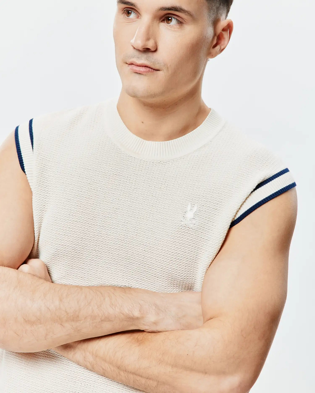 Peter Knit Vest, cream textured knit with navy double-striped ribbed armholes, classic fit, and a small embroidered Psycho Bunny skull logo on the left chest.