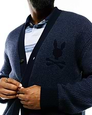 Mens Atkinson Cardigan, a relaxed fit navy blue waffle knit cardigan with ribbed cuffs and hem, featuring a large tonal embroidered Psycho Bunny skull logo on the left chest and a single visible button closure.