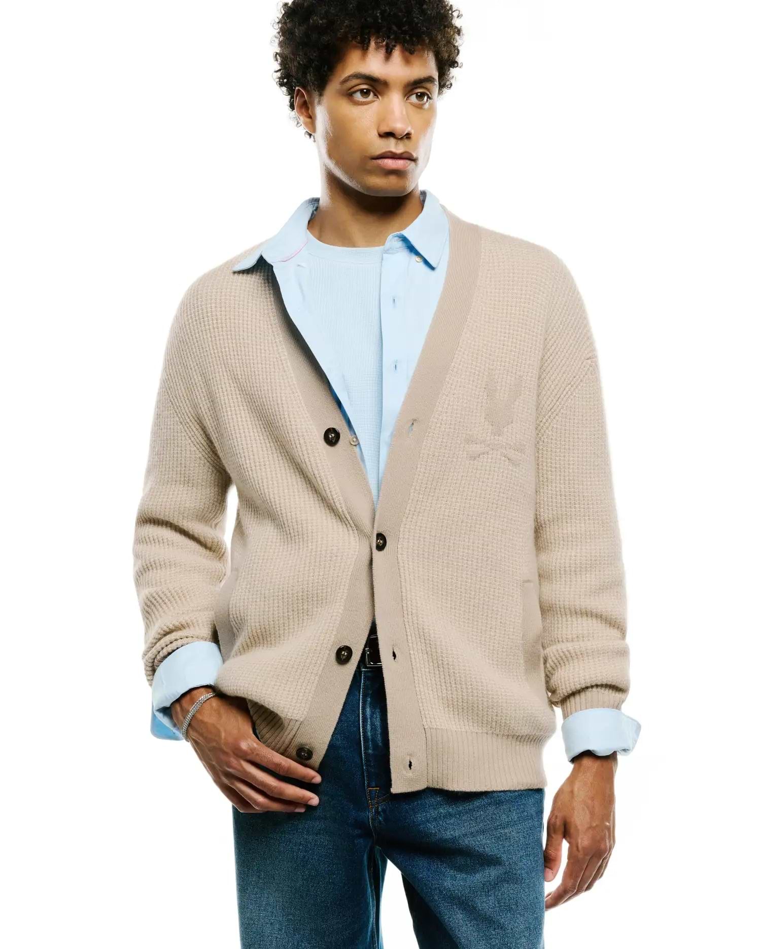 Mens Atkinson Cardigan: Classic fit beige waffle knit cardigan with dark brown buttons and a subtle tonal Psycho Bunny skull logo embroidered on the left chest.