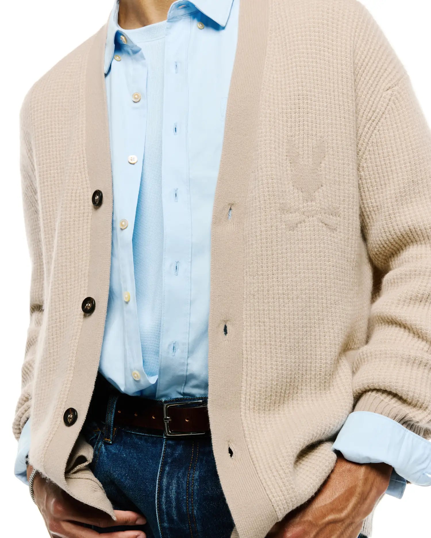 Mens Atkinson Cardigan in a relaxed fit, featuring a light beige waffle knit texture, dark brown buttons, and a subtle, tone-on-tone embroidered Psycho Bunny skull logo on the left chest.