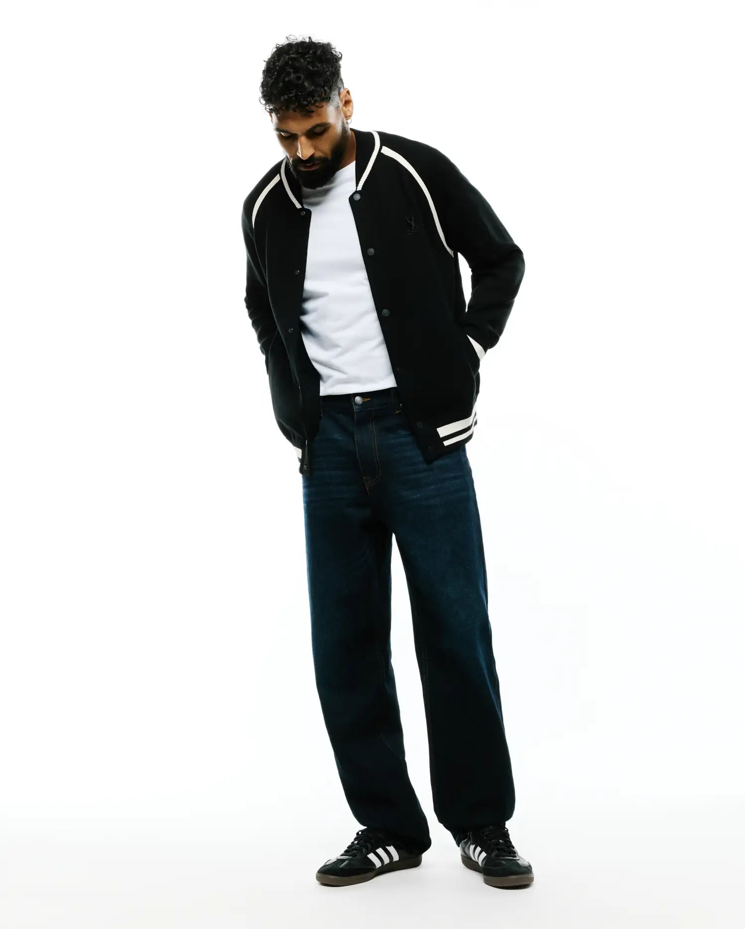 Black knit Mens Rafferty Cardigan, a classic fit varsity style featuring white shoulder piping, ribbed cuffs with double white stripes, and a small embroidered Psycho Bunny skull logo on the left chest.