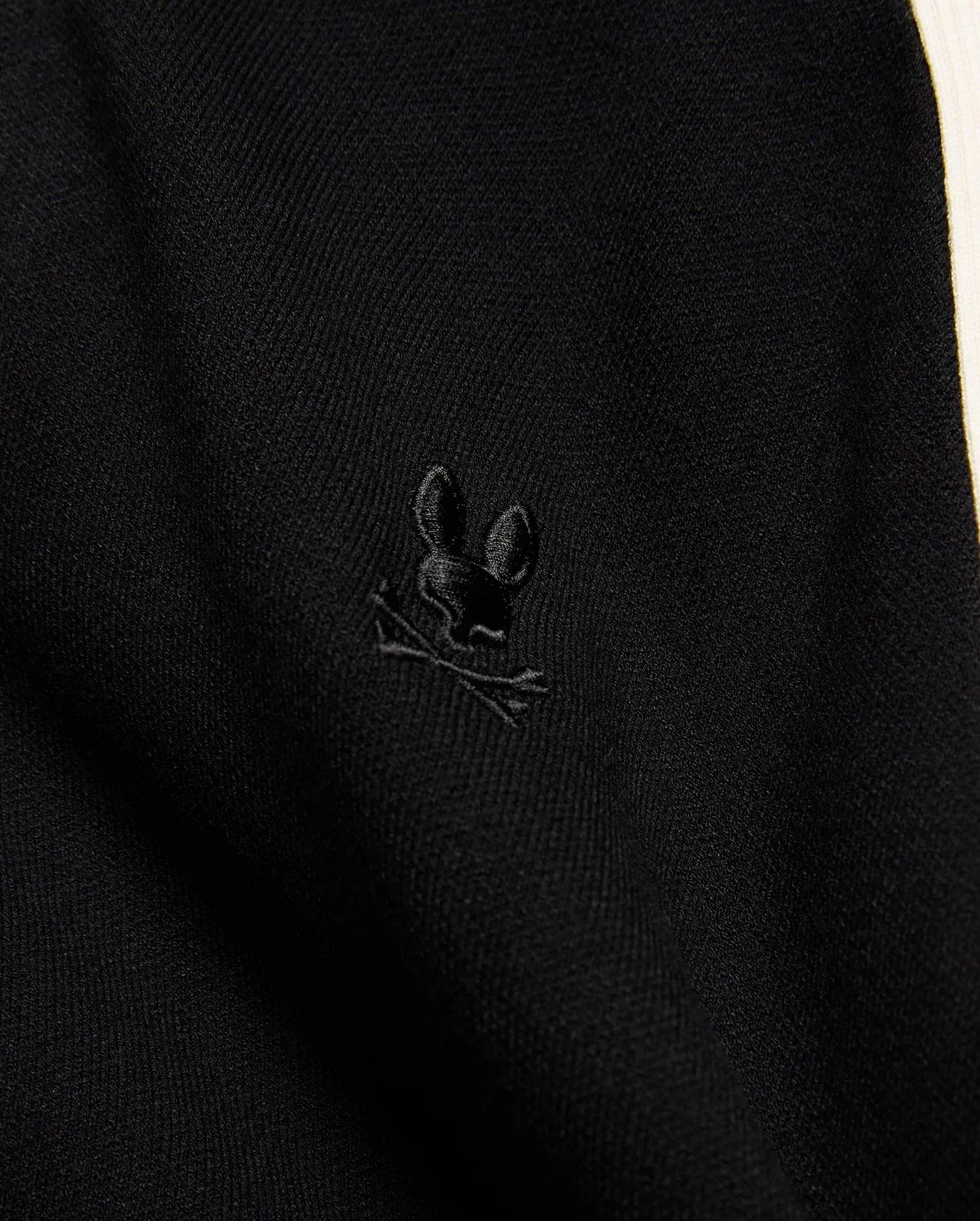 Mens Rafferty Cardigan in black fine knit fabric with a subtle ribbed texture, featuring a small, tonal black embroidered Psycho Bunny skull logo and a cream side stripe.