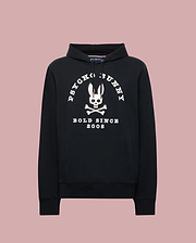 The Psycho Bunny MENS ARCHIVE HOODIE (MT0500009) is a black cotton knit pullover with a front pocket, showcasing an archive-inspired white Bunny skull and crossbones and "PSYCHO BUNNY BOLD SINCE 2005" over a light pink backdrop.