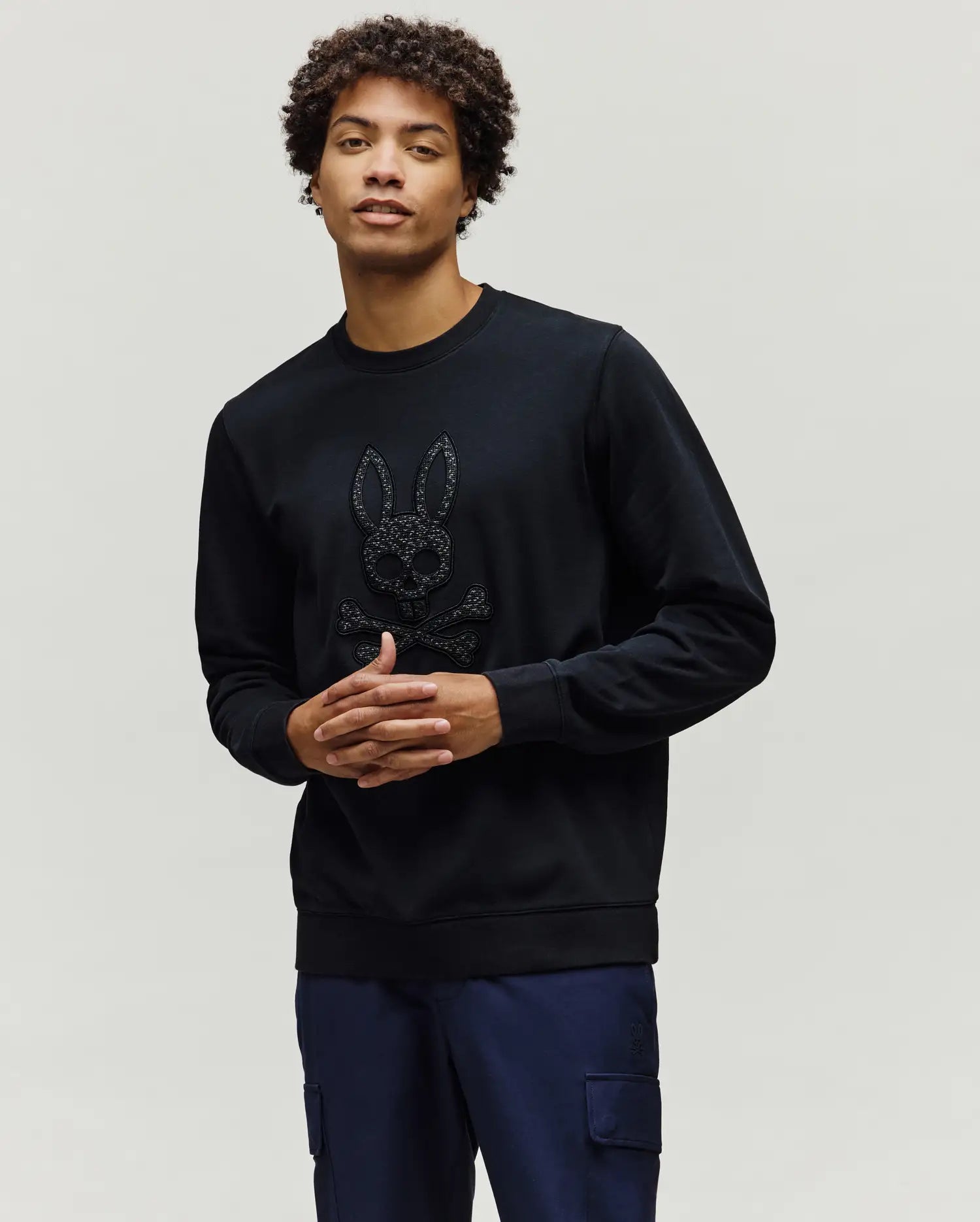 Black Mens Gabin Textured Crew sweatshirt, a classic fit crafted from textured black fabric, featuring a large, raised Psycho Bunny skull and crossbones logo on the chest.