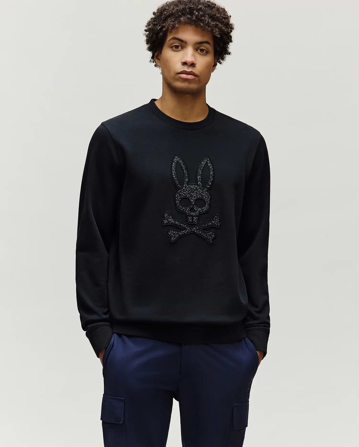 Mens Gabin Textured Crew, a black classic-fit sweatshirt featuring a large, textured Psycho Bunny skull and crossbones logo prominently on the central chest.