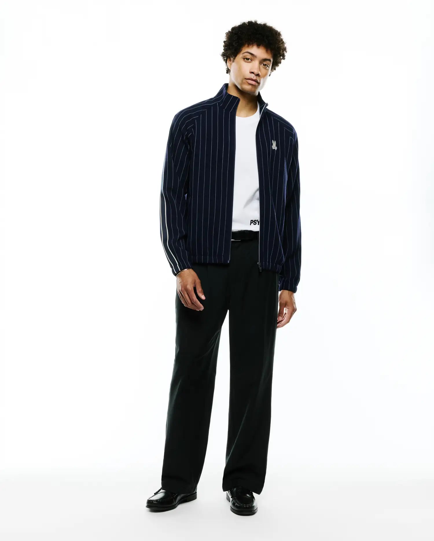 Mens Harland Double Weave Chalk Stripe Track Jacket in navy with white vertical pinstripes, a full zip, stand collar, and a small embroidered Psycho Bunny skull logo on the left chest, featuring white accent stripes on the sleeves. (5)