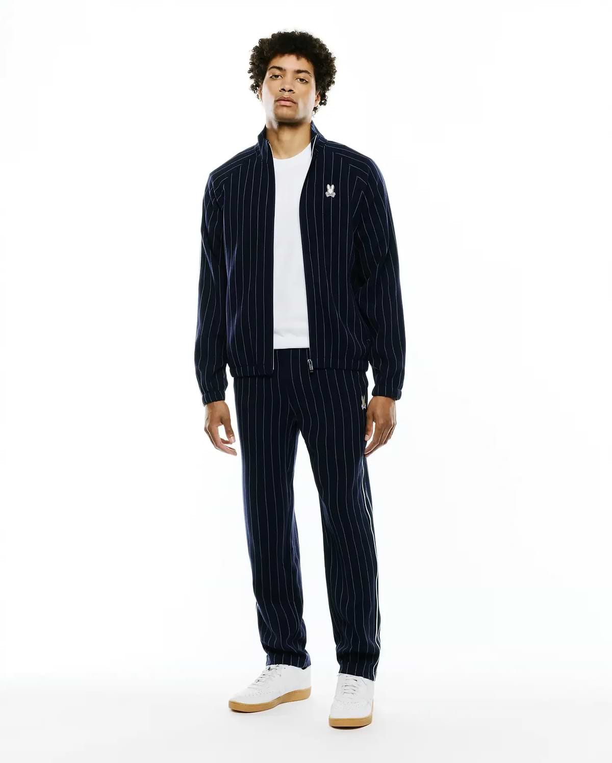 Mens Harland Double Weave Chalk Stripe Track Jacket and matching pants in navy with white vertical chalk stripes. Features a classic fit, full-zip jacket, and small embroidered white Psycho Bunny skull logos on the left chest and left thigh. (2)