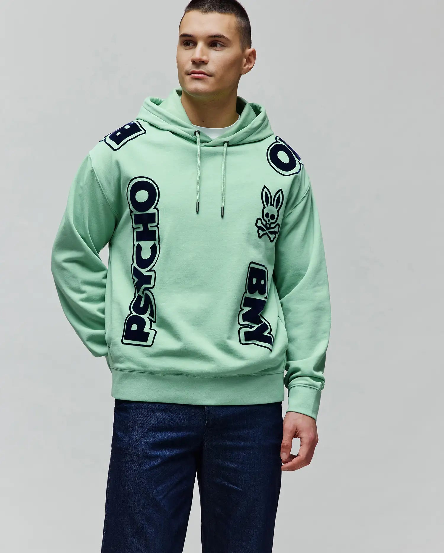 Mens Toby Oversized Hoodie in mint green french terry, featuring large navy blue PSYCHO BUNNY text with white outlines vertically on the front and a bunny skull logo on the chest.