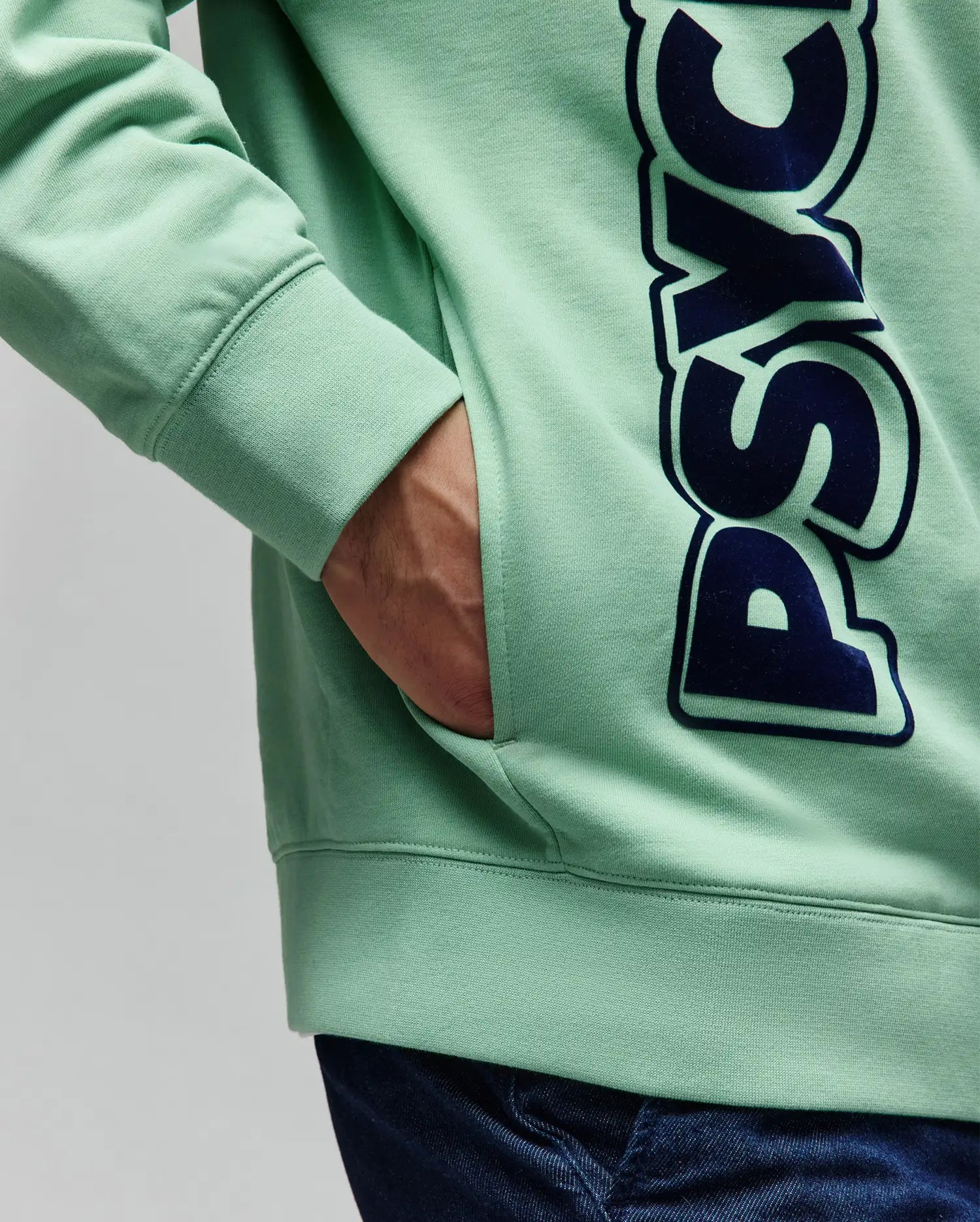 Mens Toby Oversized Hoodie in mint green French terry, featuring a large vertical dark blue PSYCHO text graphic with a subtle outline, ribbed cuffs, and a kangaroo pocket.