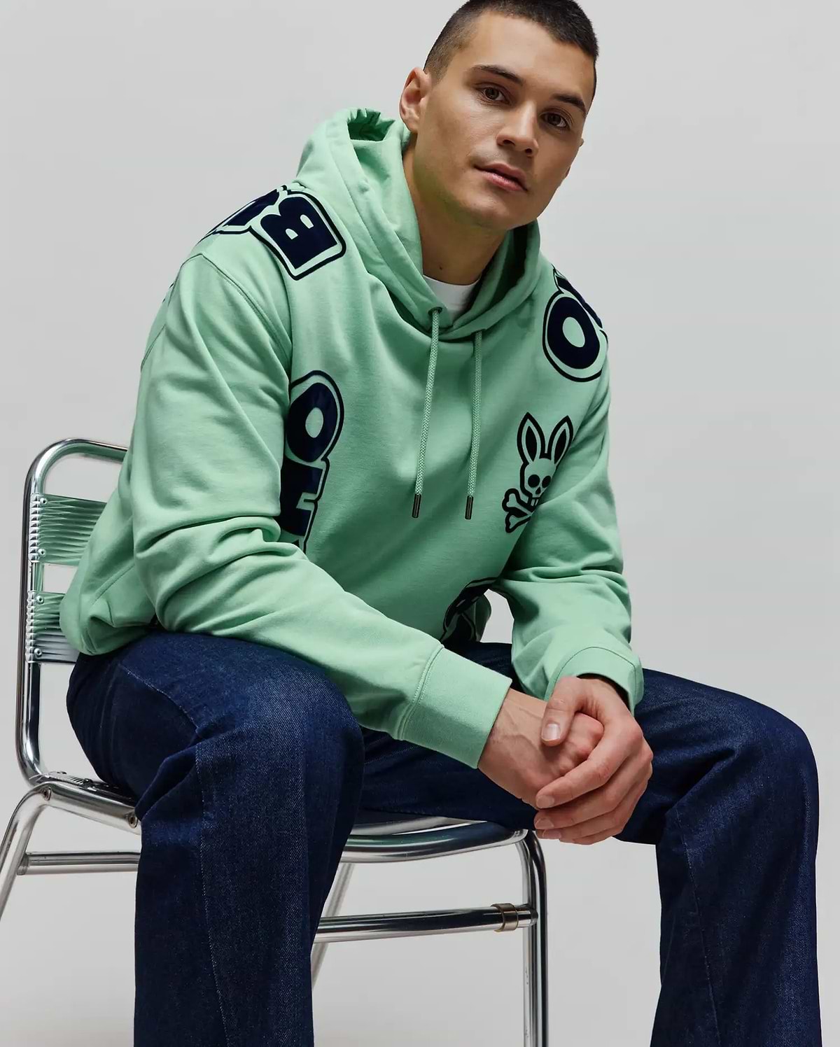 Mens Toby Oversized Hoodie in mint green, crafted from soft jersey, featuring bold dark blue Psycho Bunny lettering across the shoulders and a small bunny skull logo on the left chest.