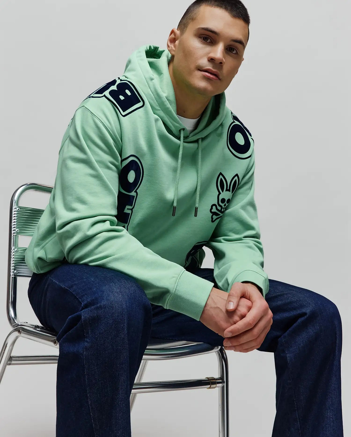 Mens Toby Oversized Hoodie in mint green, crafted from soft jersey, featuring bold dark blue Psycho Bunny lettering across the shoulders and a small bunny skull logo on the left chest.