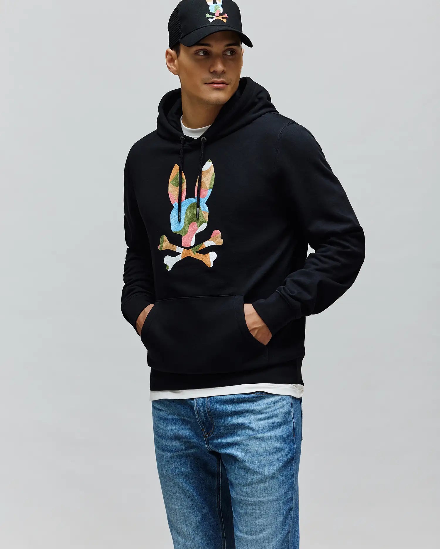 Black Mens Ara Hoodie, a classic fit French terry pullover, showcasing a prominent multicolor camouflage Psycho Bunny skull logo on the central chest.