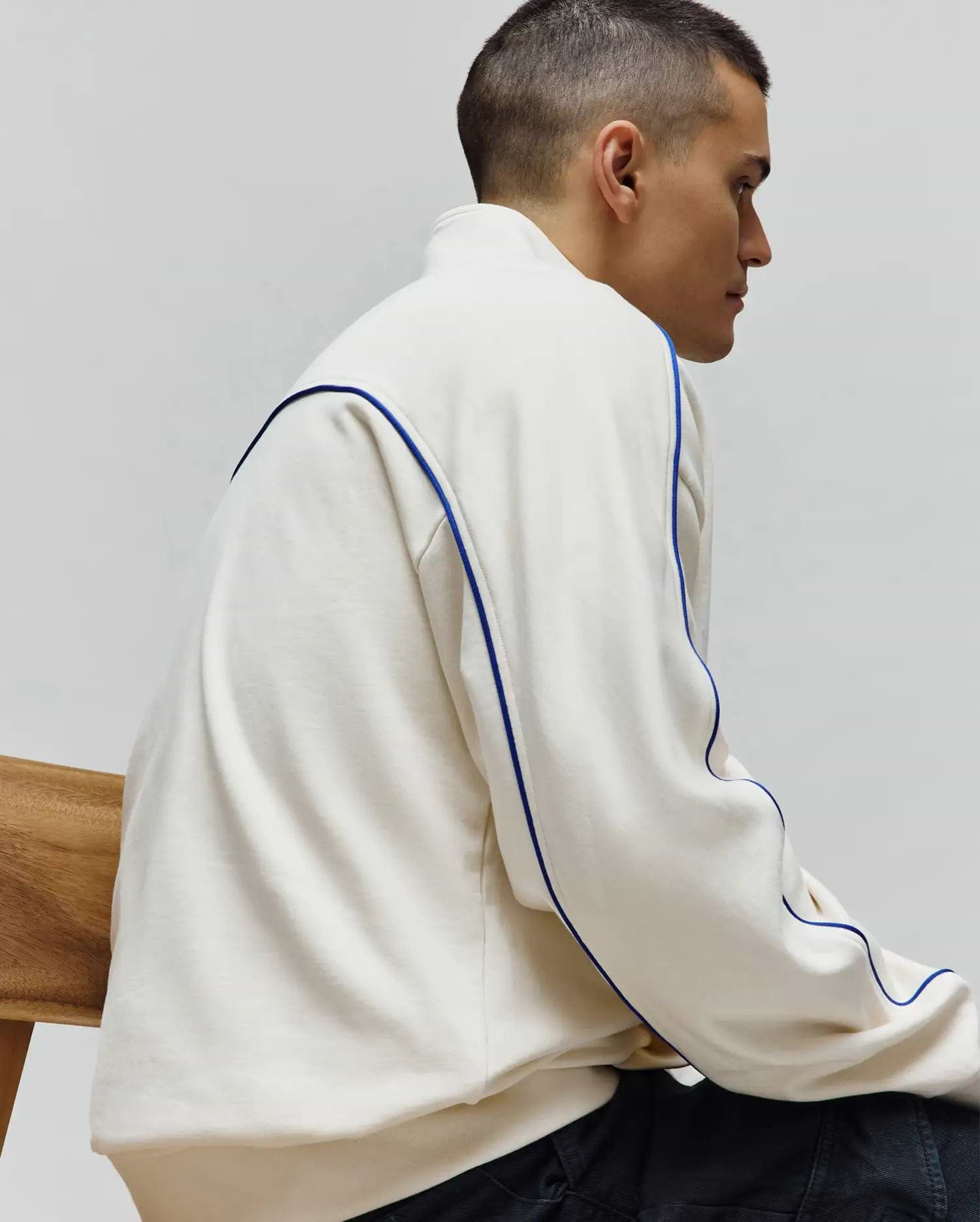 Mens Toby 1/4 Zip in cream, a relaxed fit French terry top with bold blue piping accenting the shoulders and sides. Psycho Bunny branding not visible.