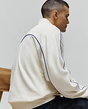 Mens Toby 1/4 Zip in cream, a relaxed fit French terry top with bold blue piping accenting the shoulders and sides. Psycho Bunny branding not visible.