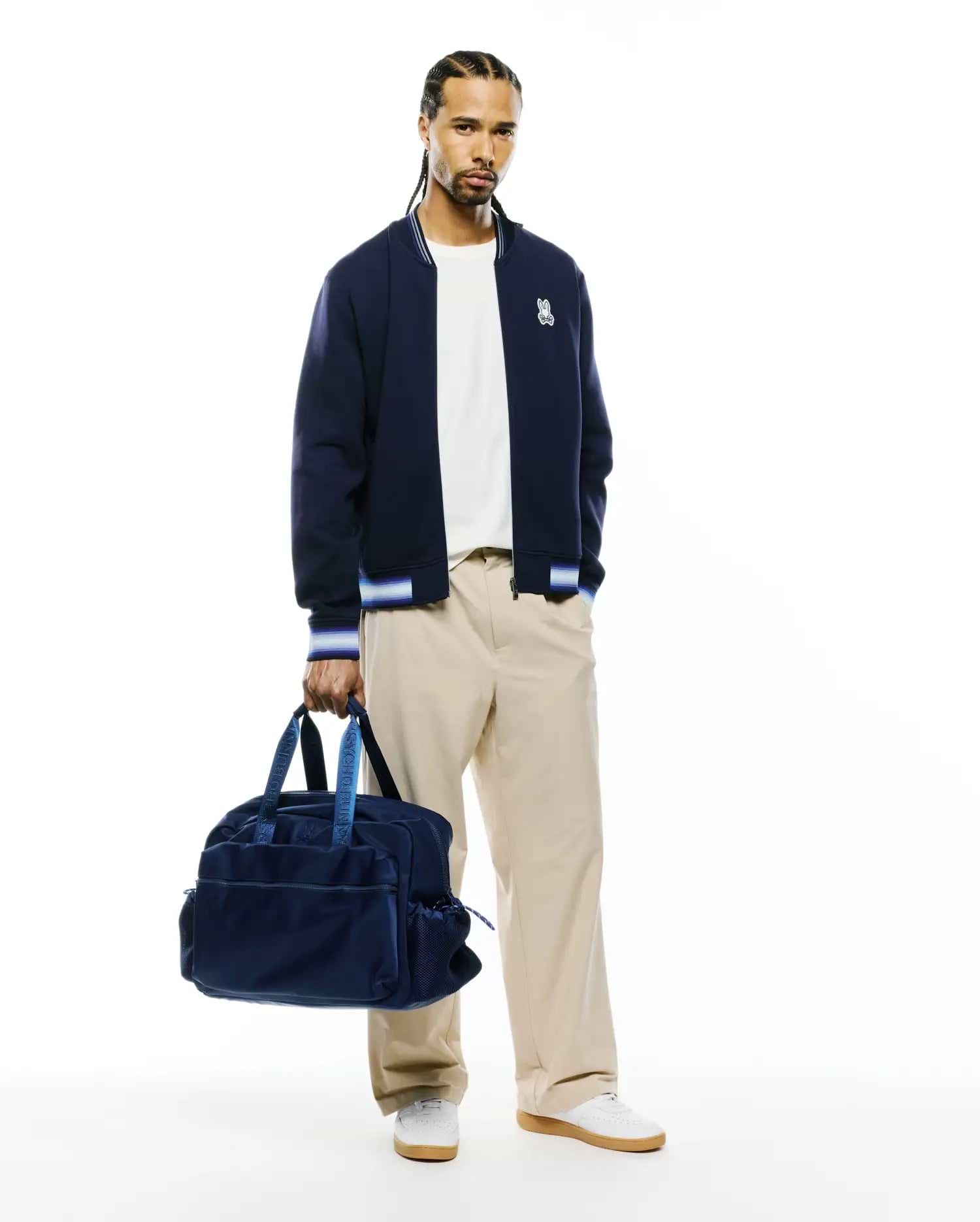 Mens Jaydon Track Jacket, navy blue with white and blue striped ribbed collar, cuffs, and hem. Features a small embroidered white Psycho Bunny skull logo on the left chest. Classic fit, smooth knit fabric. (4)