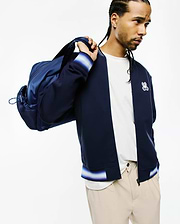Mens Jaydon Track Jacket in navy blue, a classic fit with smooth fabric, full zip, and ribbed cuffs and hem featuring white, light blue, and purple stripes. Embroidered Psycho Bunny skull logo on the left chest. (3)