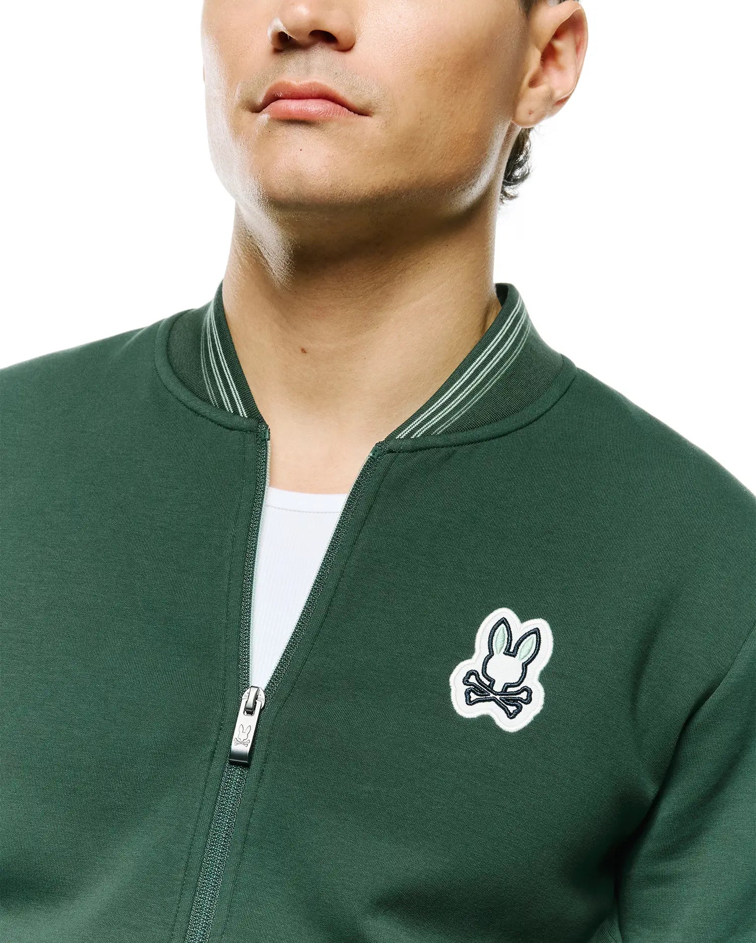 Mens Jaydon Track Jacket, forest green, smooth knit, full-zip with Psycho Bunny logo pull, embroidered white/light green bunny skull logo on left chest, and striped ribbed collar.