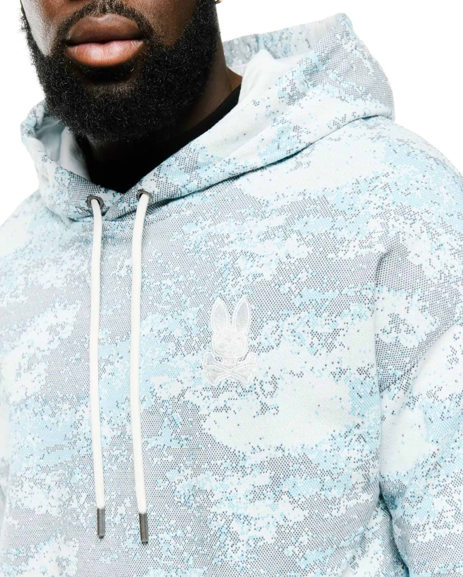 Men's Alfie All-Over Print Hoodie in light blue, white, and grey pixelated digital camo print, featuring a classic fit, soft knit fabric, and an embroidered white Psycho Bunny skull logo on the left chest with white drawstrings. (3)