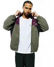 Mens Alder Nylon Colorblock Jacket: Relaxed fit olive green, purple, and black crinkled nylon full-zip jacket featuring a colorblock design, elastic cuffs, and Psycho Bunny text on the chest.