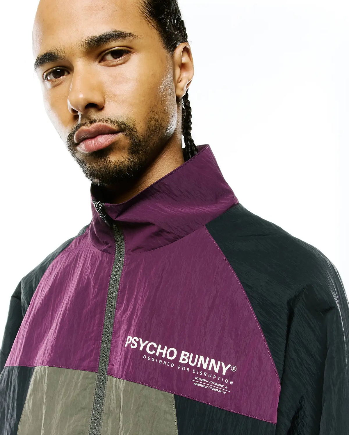 Mens Alder Nylon Colorblock Jacket in purple, dark grey, olive, with crinkled texture, full-zip, high collar, and white Psycho Bunny text logo with Designed For Disruption and coordinates on chest.