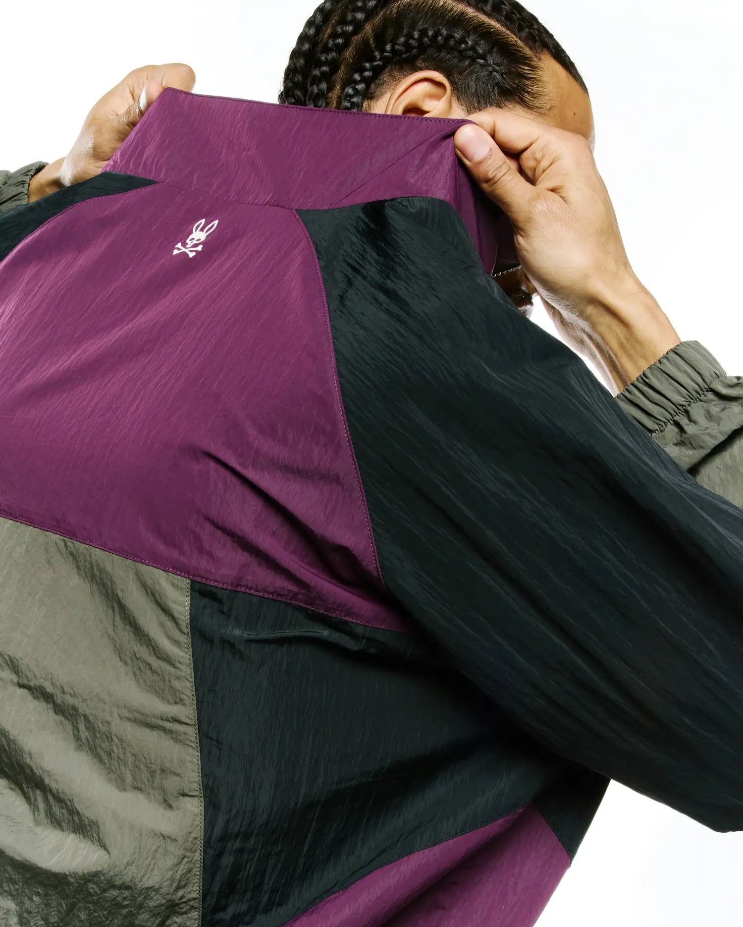 Mens Alder Nylon Colorblock Jacket in plum, black, and olive green crinkled nylon, featuring a small white embroidered Psycho Bunny skull logo on the upper back.