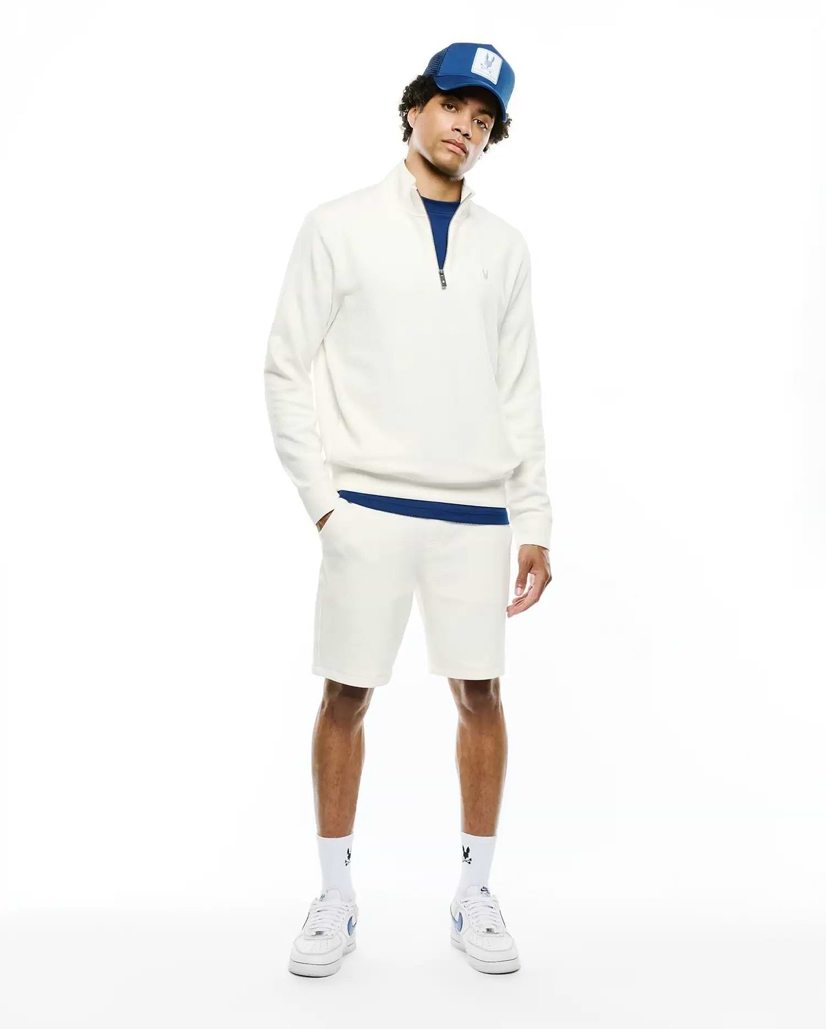 Mens Marc Textured 1/4 Zip in cream, a classic fit textured knit pullover with a small embroidered Psycho Bunny skull logo on the chest, accented by royal blue underlayer and matching shorts.