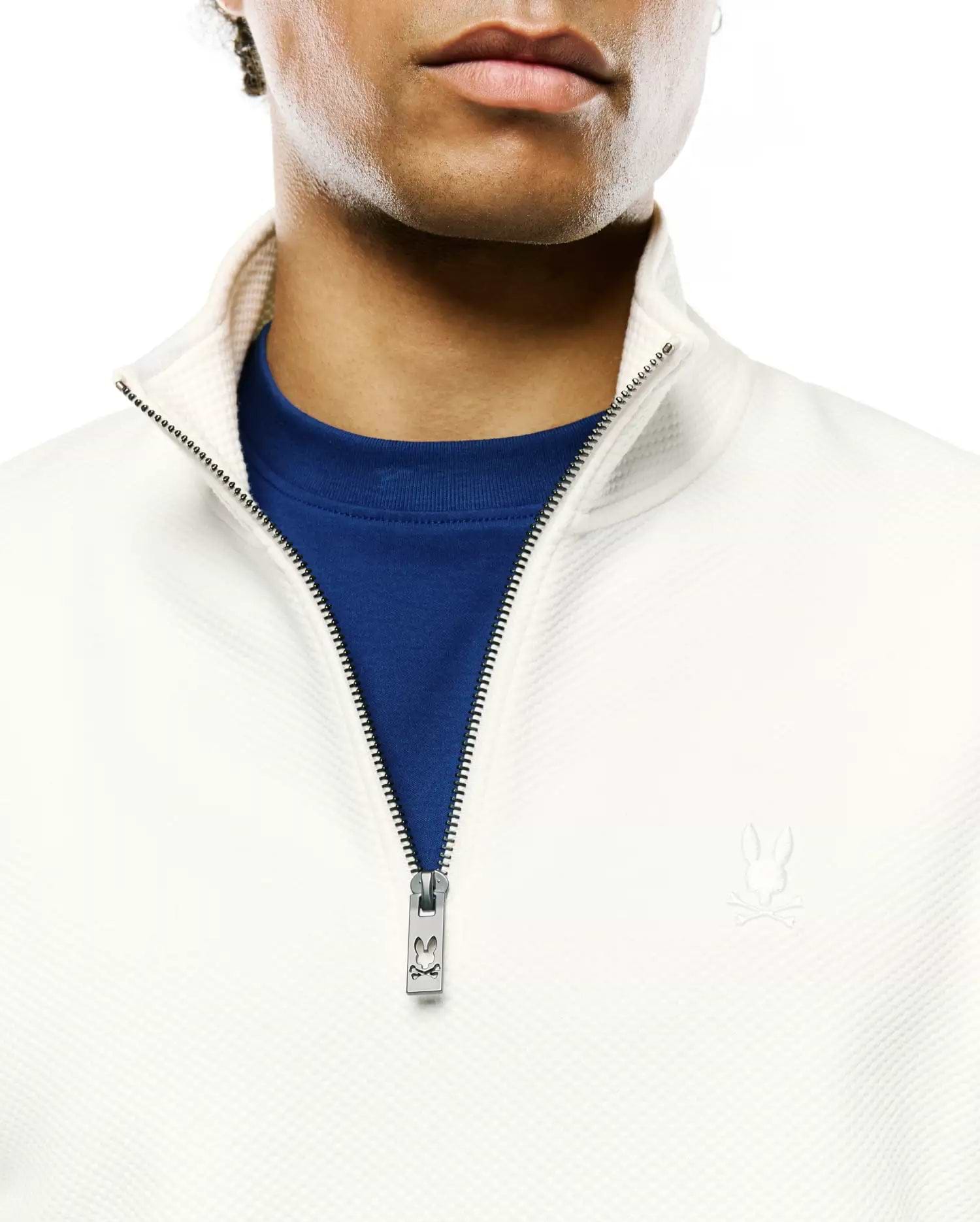Cream Mens Marc Textured 1/4 Zip with a subtle diamond knit, royal blue undershirt, silver Psycho Bunny logo zipper pull, and small embroidered bunny skull on the left chest.