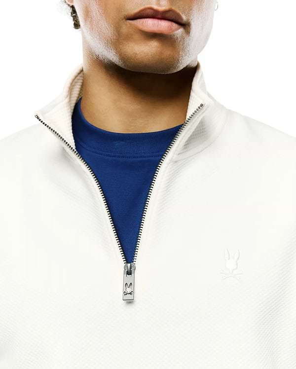 Cream Mens Marc Textured 1/4 Zip with a subtle diamond knit, royal blue undershirt, silver Psycho Bunny logo zipper pull, and small embroidered bunny skull on the left chest.