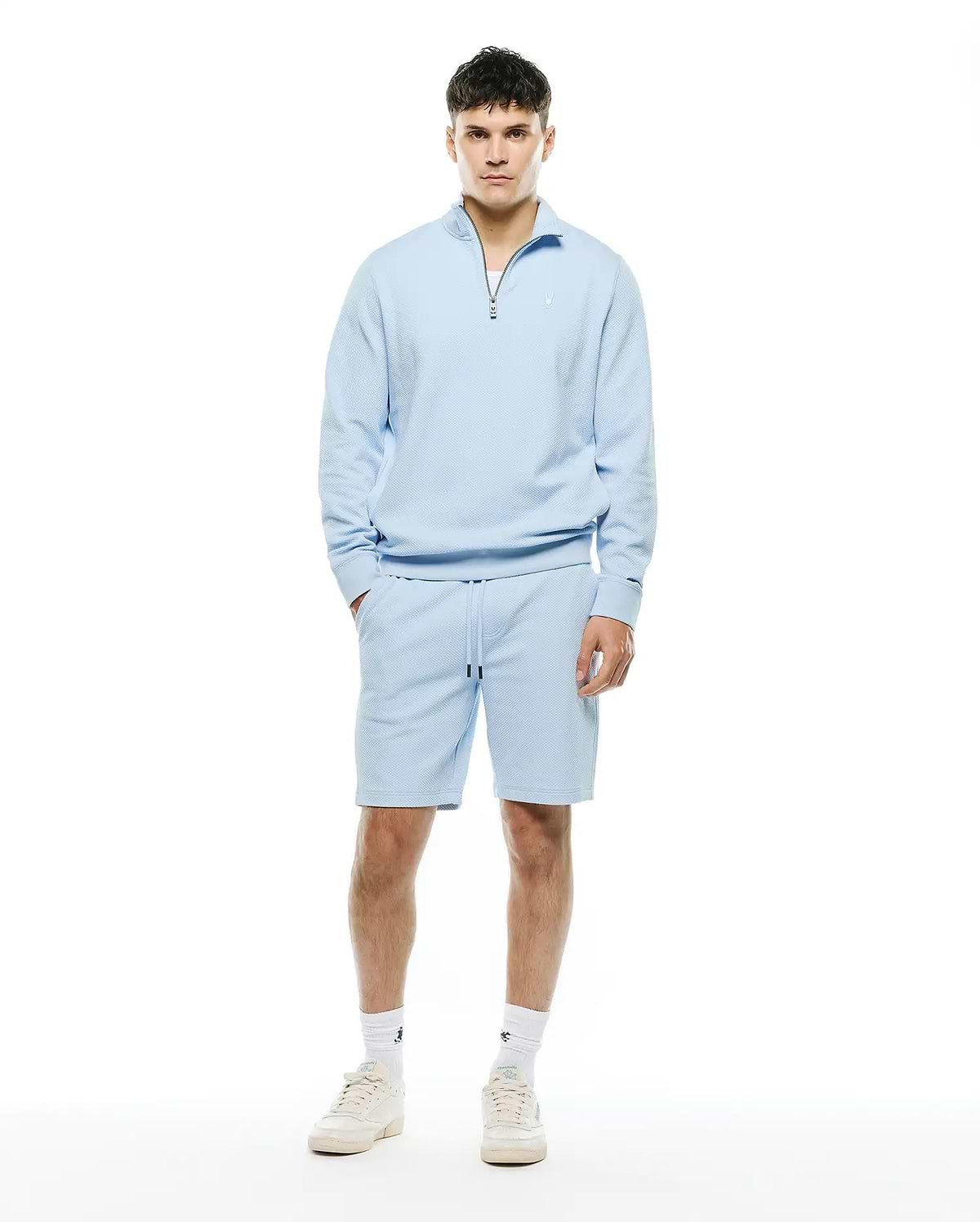 Light blue Mens Marc Textured 1/4 Zip and matching textured shorts, featuring a relaxed fit, silver quarter-zip, and small embroidered Psycho Bunny skull logo on the left chest.