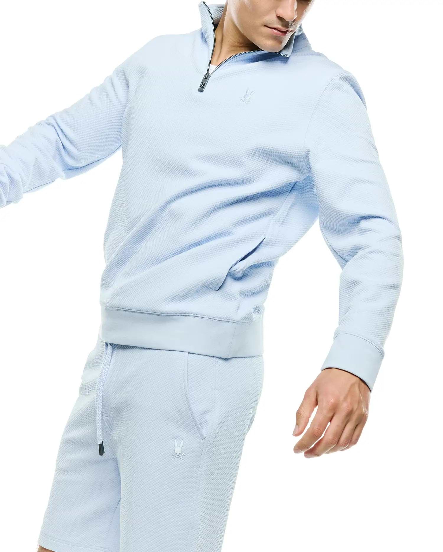 Light blue Mens Marc Textured 1/4 Zip pullover and matching shorts, both featuring a subtle waffle knit texture, a dark grey 1/4 zip, and small embroidered Psycho Bunny skull logos on the chest and left thigh.