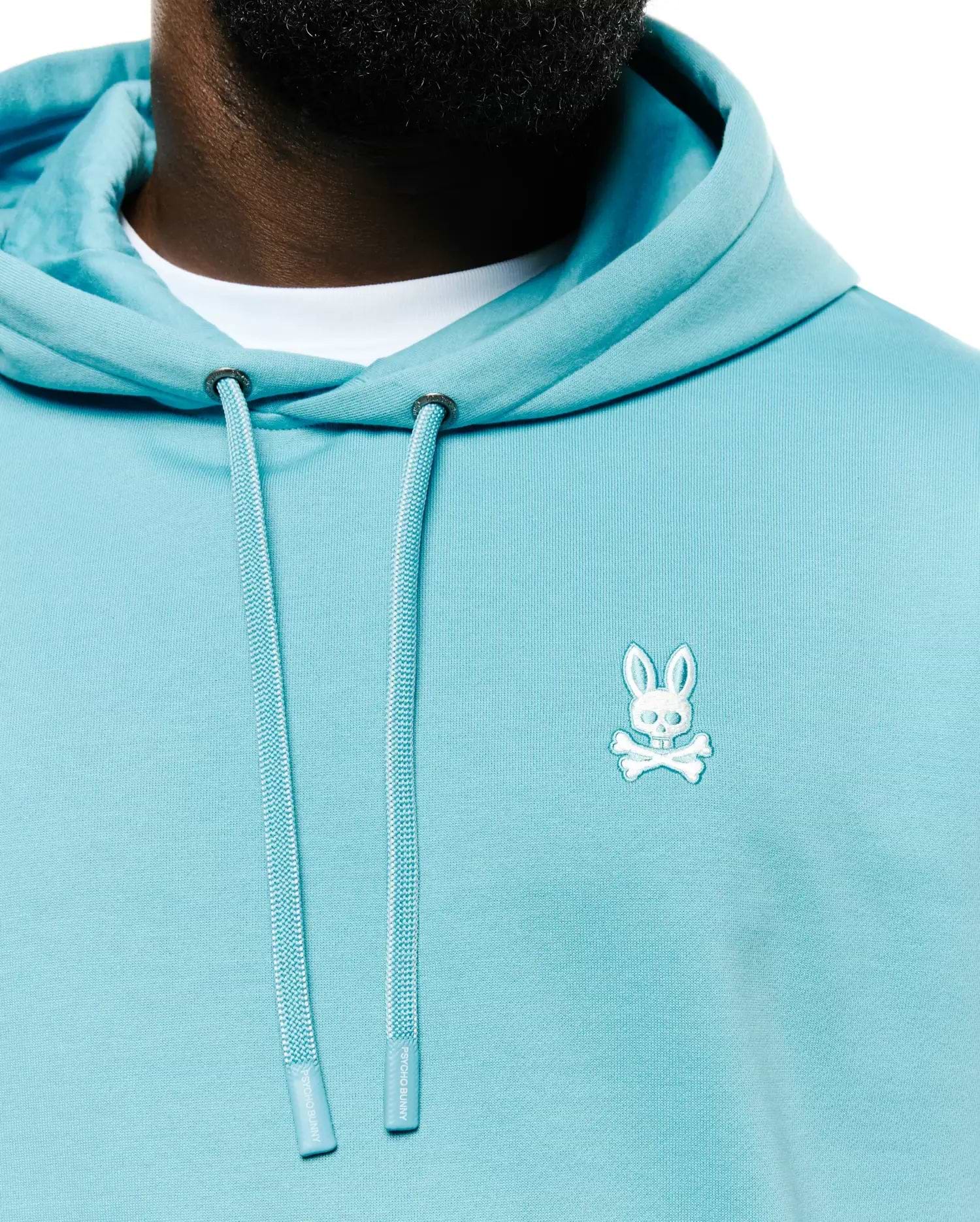 Men's Terrence Fleece Hoodie in aqua blue, featuring a classic fit, smooth fleece fabric, and a small white embroidered Psycho Bunny skull logo on the left chest. Drawstrings have Psycho Bunny branded tips. (2)