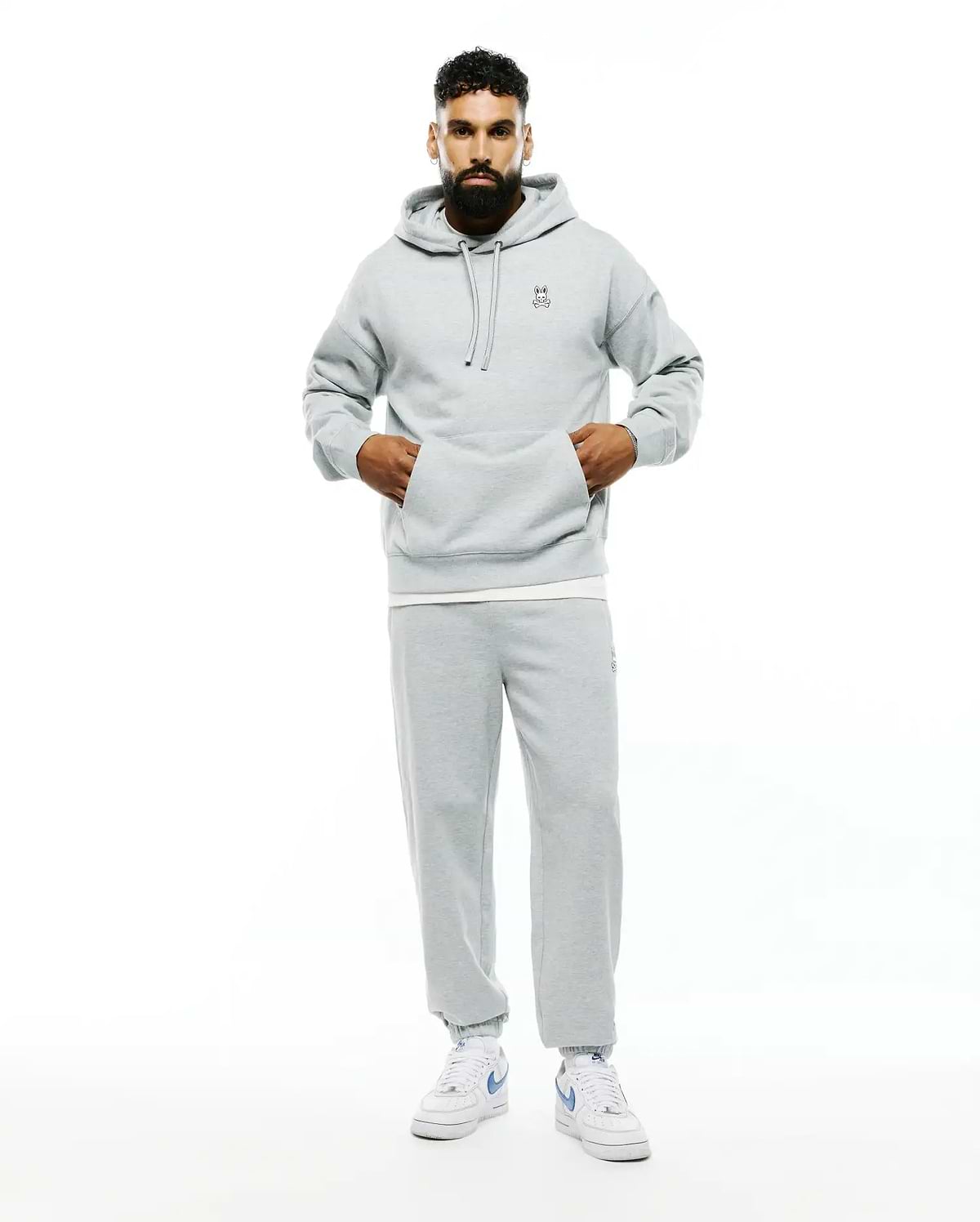 Mens Terrence Fleece Hoodie in light grey, featuring a relaxed fit, soft French terry fabric, drawstring hood, kangaroo pocket, and a small embroidered Psycho Bunny skull logo on the left chest.