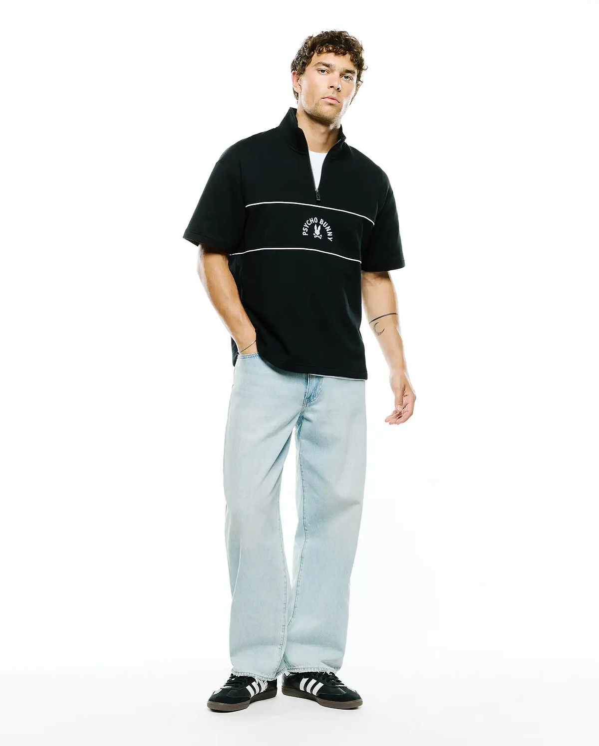 Mens Stevie French Terry Ss 1/4 Zip in black, featuring a relaxed fit, soft french terry fabric, two white horizontal chest stripes, and a white Psycho Bunny skull logo centered on the chest.