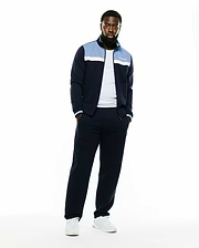 Men's Jacques Pique Track Jacket in navy, featuring a classic fit, light blue and white color-block chest panels, a white embroidered Psycho Bunny script logo on the left chest, and striped ribbed cuffs. (1)