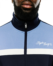 Jacques Pique Track Jacket in navy and light blue color-block pique, featuring a white horizontal stripe, embroidered white Psycho Bunny script logo on the left chest, and a bunny skull zipper pull. (3)
