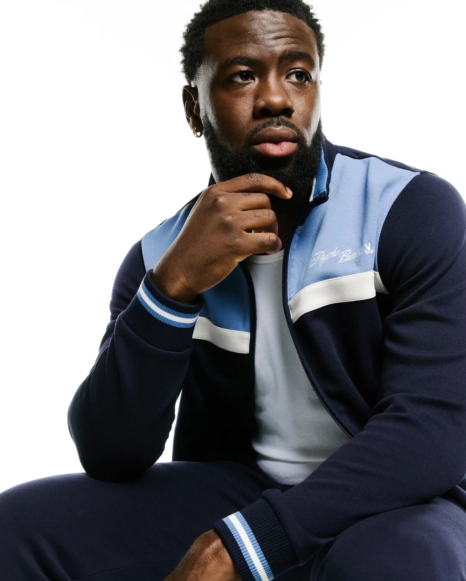 Men's Jacques Pique Track Jacket in navy with light blue and white color-blocked panels, featuring a full zip, ribbed cuffs with stripes, and an embroidered white Psycho Bunny script logo on the left chest. (4)