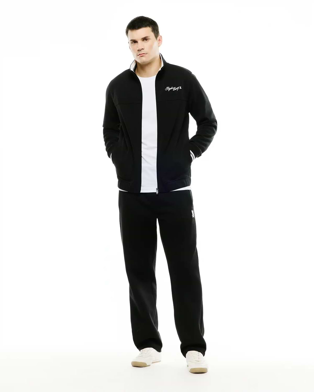 Men's Jacques Pique Track Jacket in black, classic fit, with white collar lining, striped cuffs, and embroidered script logo. Paired with black relaxed fit sweatpants featuring an embroidered bunny skull logo. (1)