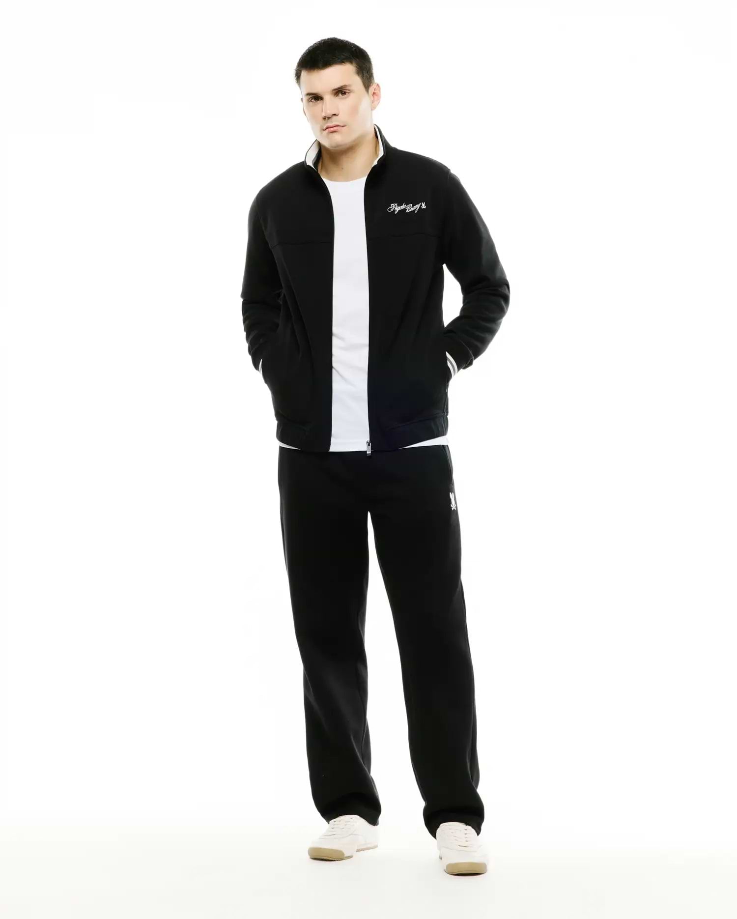 Men's Jacques Pique Track Jacket in black, classic fit, with white collar lining, striped cuffs, and embroidered script logo. Paired with black relaxed fit sweatpants featuring an embroidered bunny skull logo. (1)