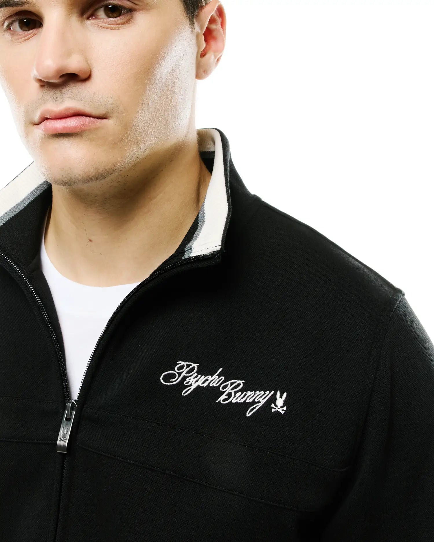 Men's Jacques Pique Track Jacket, black, classic fit, with white and grey striped ribbed collar, full zip with Psycho Bunny skull pull, and embroidered white script logo on left chest. (3)
