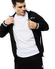 Men's Jacques Pique Track Jacket, black, featuring a full zip, white ribbed collar, striped cuffs, side stripe, and embroidered Psycho Bunny script on sleeve, layered over a white tee with a pink bunny skull logo. (4)