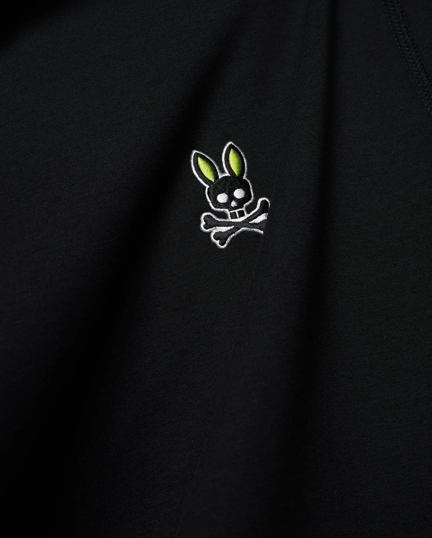 Mens Lex Hoodie, black smooth knit, featuring a small embroidered Psycho Bunny skull logo on the chest with vibrant neon green ears, black skull, and white outline details. (6)