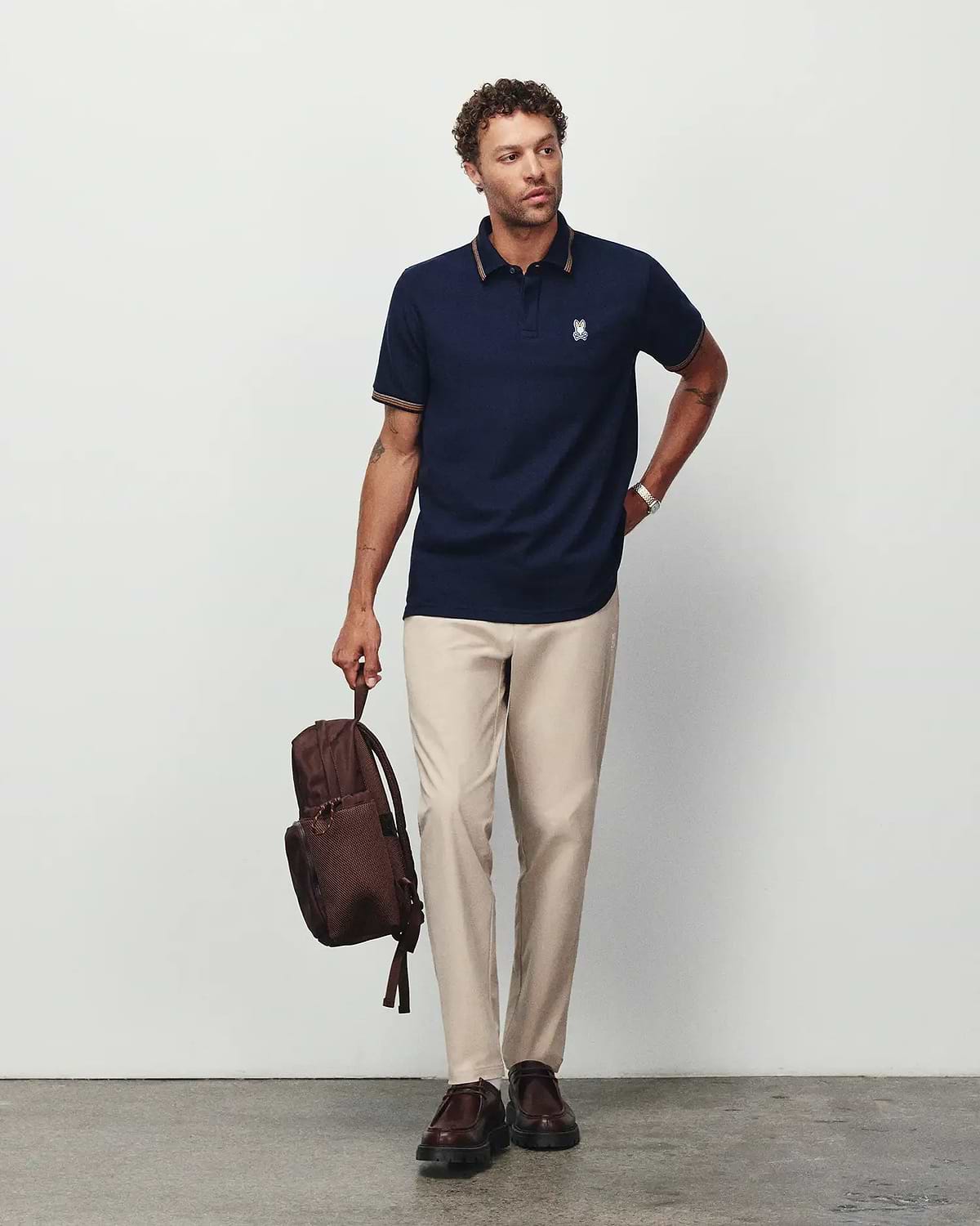 Mens Jaydon Pique Polo in navy, featuring a classic fit, pique texture, and small embroidered Psycho Bunny skull logo on the left chest with gold tipping on the collar and cuffs.