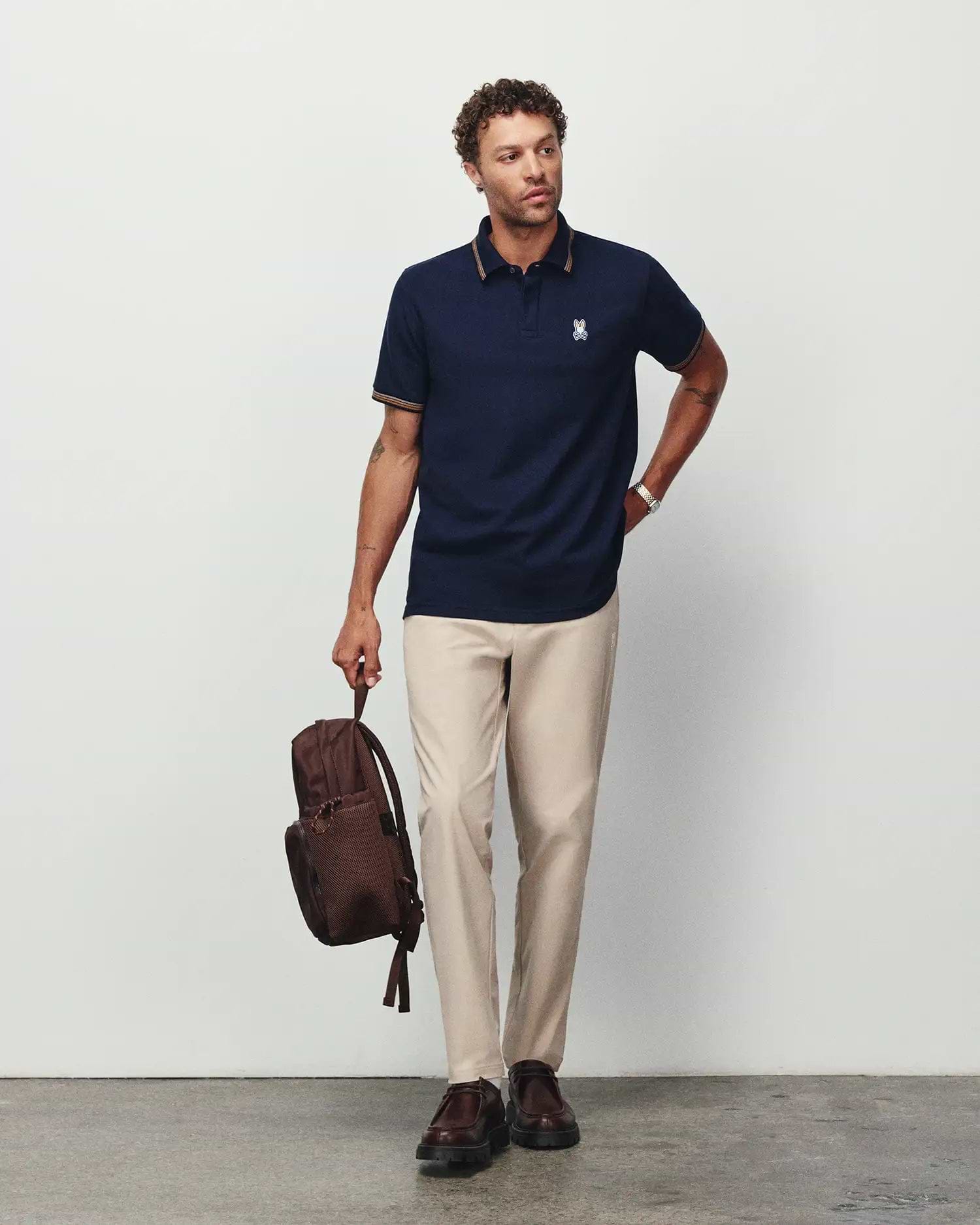 Mens Jaydon Pique Polo in navy, featuring a classic fit, pique texture, and small embroidered Psycho Bunny skull logo on the left chest with gold tipping on the collar and cuffs.