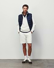 Mens Marc Textured Short in cream pique with a small embroidered Psycho Bunny logo on the left thigh, styled with a matching textured quarter-zip pullover featuring a chest logo and a navy quilted vest.